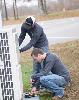 Commercial HVAC Services showing technicians repairing an outdoor commercial AC unit.